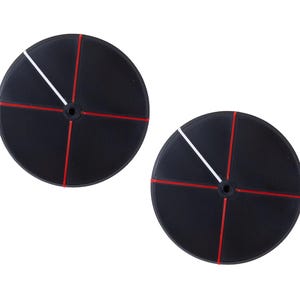 Könnte beinhalten: Zwei schwarze kreisförmige Objekte mit roten und weißen Linien. Jedes Objekt hat eine weiße Diagonallinie und ein rotes Kreuz. Die Objekte haben ein kleines Loch in der Mitte.