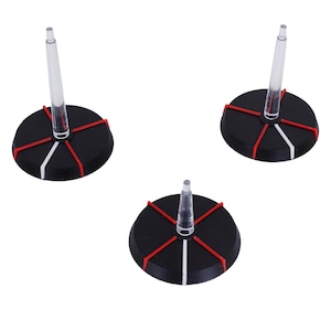 Könnte beinhalten: Drei schwarze, kreisförmige Präsentationsständer mit einem transparenten, vertikalen Pfosten. Jeder Ständer hat rote und weiße Akzentlinien, die von der Mitte ausgehen. Die Ständer sind für kleine Objekte konzipiert.