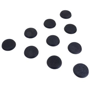 Könnte beinhalten: Zehn kleine, runde, schwarze Objekte liegen auf weißem Hintergrund. Jedes Objekt hat eine leicht gewölbte Form und eine strukturierte Oberfläche. Die Objekte sind unterschiedlich ausgerichtet.
