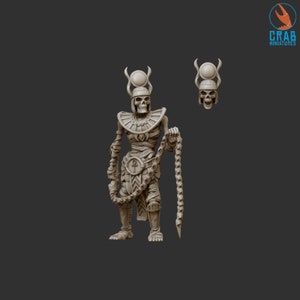 Könnte beinhalten: Beige Miniatur eines ägyptischen Pharao-Skeletts, das eine Kette hält. Die Figur trägt eine Kopfbedeckung und einen Kragen. Ein separater Schädel mit derselben Kopfbedeckung ist ebenfalls sichtbar. Das Crab Miniatures-Logo befindet sich in der oberen rechten Ecke.