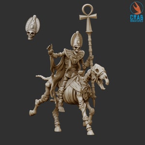 Könnte beinhalten: Beige Miniatur eines Skeletts auf einem Skelettpferd, das einen Stab mit einem Ankh-Symbol hält. Die Figur trägt eine Kopfbedeckung und einen Umhang. Ein abgetrennter Schädel ist ebenfalls vorhanden. Das Crab Miniatures-Logo befindet sich oben rechts.