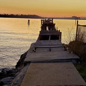 An old pier leading to the river in the light of the sunset, New York City