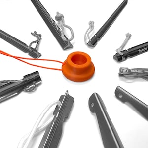 May include: An assortment of black tent stakes with attached cords and an orange stake puller. The stakes are arranged in a circle, with the puller in the center. Some stakes have brand names printed on them.