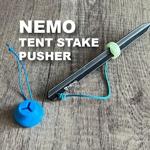 May include: A black tent stake pusher with a blue rope and a blue plastic handle. The tool is labeled "NEMO".