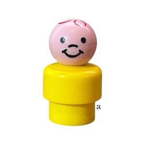 May include: A vintage Fisher-Price Little People figure. The figure has a pink head with a smiling face and red hair details. The body is yellow. The figure is a classic toy.
