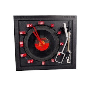 Könnte beinhalten: Eine schwarze Schallplattenuhr mit roten Würfeln als Ziffern. Das Zifferblatt ist eine schwarze Schallplatte mit einem roten Etikett, auf dem "Atlantic" steht.