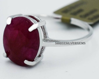 Puede incluir: Un anillo de plata con una gran piedra preciosa de rubí de forma ovalada. El anillo está engastado en un diseño simple y elegante. La banda es fina y lisa. El rubí es de color rojo intenso y tiene un alto pulido. El anillo está hecho por Shree Silver Gems.