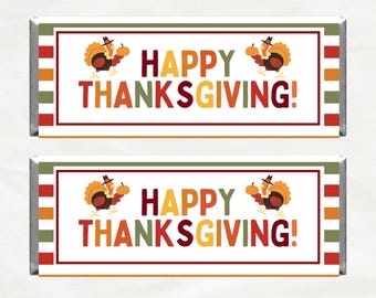 May include: Two candy bar wrappers with a Thanksgiving theme. Each wrapper has a white background with the words "HAPPY THANKSGIVING!" in colorful letters. A cartoon turkey holding a pumpkin is on each wrapper.