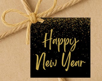 May include: A gift tag with the words "Happy New Year" in gold script on a black background, with gold glitter accents. The tag is tied with natural twine and a bow, set against a brown paper backdrop.
