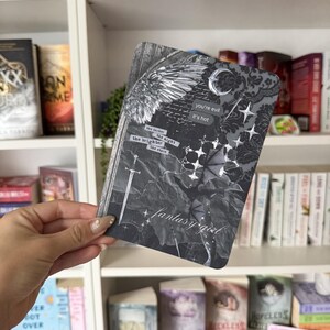 May include: A rectangular card featuring a dark, collage-style design with a large wing, a sword, a crescent moon, and stars. Text on the card reads: you're evil, it's hot, the darker the night the brighter the stars, and fantasy girl.