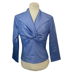 May include: A blue, long-sleeved blouse with a twist detail at the front. The blouse has a v-neck and a fitted silhouette.