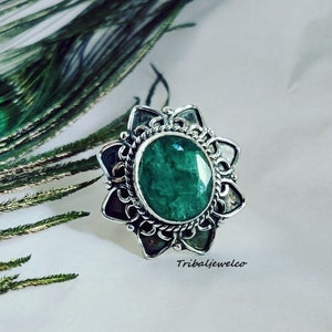 Könnte beinhalten: Ein silberner Ring mit einem großen, runden, grünen Edelstein, der in einem floralen Design gefasst ist.