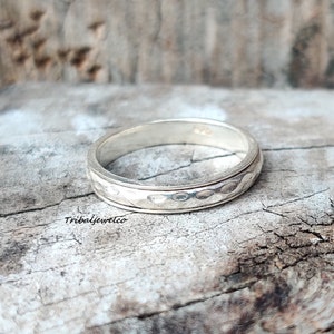 May include: A silver ring with a hammered texture. The ring is simple and elegant, and would make a great gift for a special occasion.