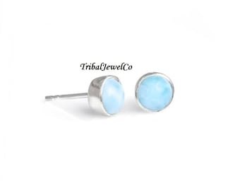 May include: A pair of silver stud earrings with round blue-green gemstone accents.