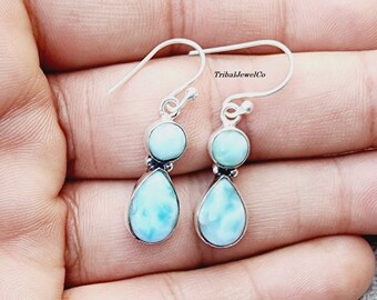 Könnte beinhalten: Ein Paar silberne Ohrhänger mit zwei tropfenförmigen blauen und weißen Edelsteinen. Die Ohrringe haben einen Hakenverschluss.
