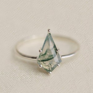May include: A silver ring with a green agate gemstone in a faceted, kite-shaped setting.