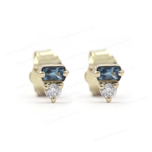 May include: A pair of gold stud earrings with a small blue gemstone and a tiny diamond accent.