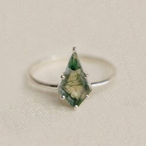 May include: A silver ring with a green and white agate gemstone in a kite shape.