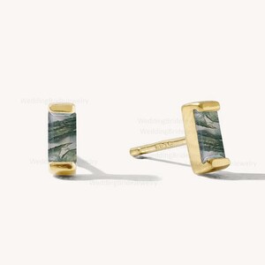 May include: A pair of gold stud earrings with a rectangular green and gray stone.