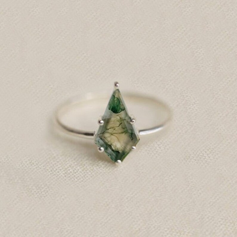 May include: A silver ring with a green and white agate gemstone in a kite shape.