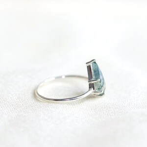May include: A silver ring with a pear-shaped green agate gemstone.