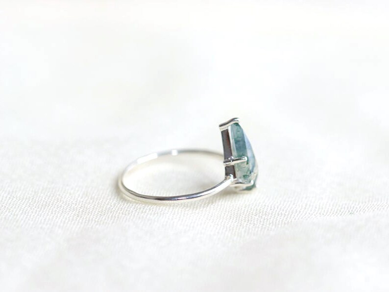 May include: A silver ring with a pear-shaped green agate gemstone.