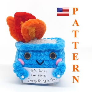 Könnte beinhalten: Ein gehäkeltes blaues Plüschtier mit einer roten und orangenen Flamme oben drauf. Das Spielzeug hält ein Schild mit der Aufschrift "Es ist in Ordnung, mir geht es gut, Alles ist in Ordnung!"