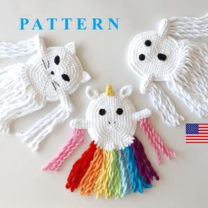 May include: Three crocheted stuffed toys: a white ghost with black eyes, a white cat with black eyes and nose, and a white unicorn with a rainbow mane and a pink horn. The toys are all handmade and have a whimsical, childlike charm.