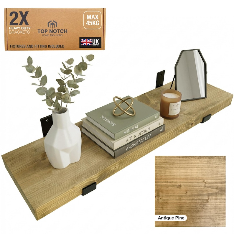 A wooden floating shelf in antique pine, supported by black brackets. It displays a white vase with foliage, books, a candle, and a mirror. The shelf is rated for a maximum weight of 45 kg.