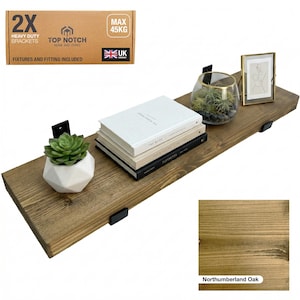 Northumberland Oak Stain wooden shelf, supported by black metal brackets, with a succulent, books, and a framed picture. The shelf can hold up to 45 kg. The packaging reads "2X Heavy Duty Brackets" and "UK Company".