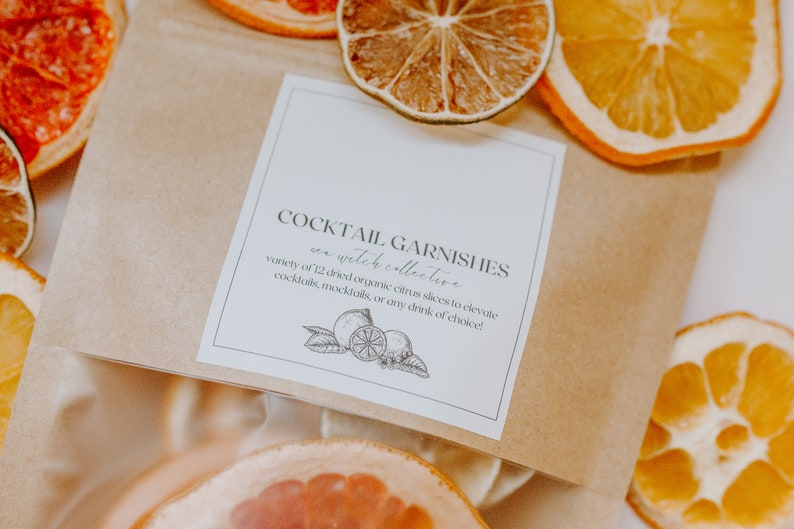 May include: A brown paper bag filled with dried citrus slices for cocktail garnishes. The bag has a white label that reads "Cocktail Garnishes - an witch collective - variety of 12 dried organic citrus slices to elevate cocktails, mocktails, or any drink of choice!"