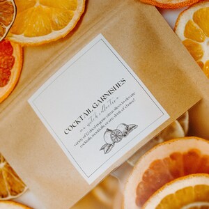 May include: A brown paper bag with a white label that reads "COCKTAIL GARNISHES sea witch collective variety of 12 dried organic citrus slices to elevate cocktails, mocktails, or any drink of choice!" The bag is filled with dried citrus slices in various colours, including orange, yellow, and red.
