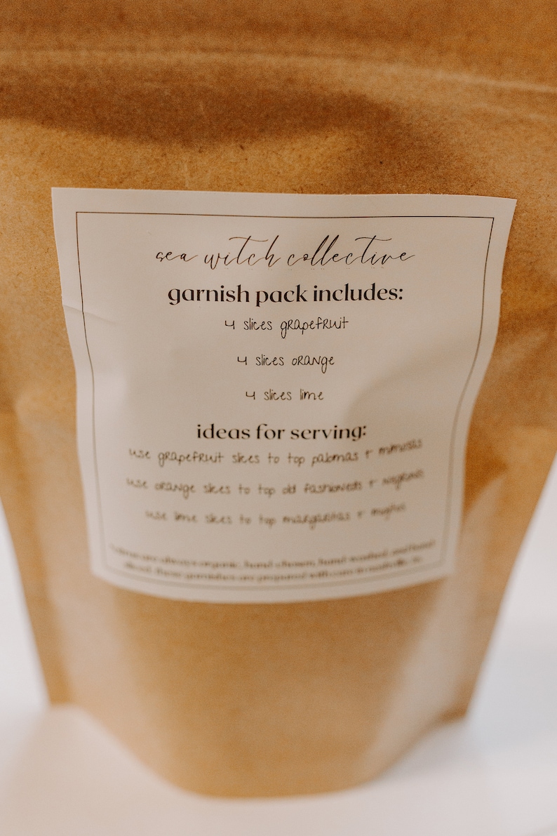 May include: A brown paper bag with a white label that says "sea witch collective garnish pack includes: 4 slices grapefruit 4 slices orange 4 slices lime ideas for serving: use grapefruit slices to top palomas & mimosas use orange slices to top old fashioneds & negronis use lime slices to top margaritas & mojitos"