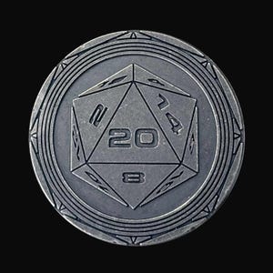 May include: A silver-colored, round coin featuring a 20-sided die at the center. The die is prominently marked with the number 20. The coin has an outer decorative border with geometric patterns, and is set against a black background.