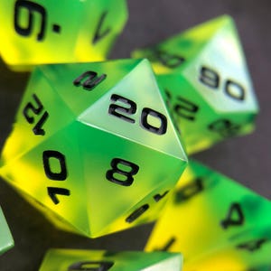 May include: A collection of polyhedral dice featuring a vibrant gradient of neon yellow and bright green. Each die has sharp edges and is marked with bold, black, easy-to-read numbers. The twenty-sided die is prominently displayed in the center.