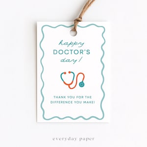 Puede incluir: Etiqueta de regalo blanca con un borde festoneado turquesa y una cuerda marrón. La etiqueta dice "happy DOCTOR'S day!" con un gráfico de estetoscopio naranja y turquesa. El texto "THANK YOU FOR THE DIFFERENCE YOU MAKE!" está debajo.