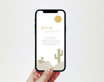 May include: A smartphone displays a digital invitation for a "Fun Fiesta" first birthday party. The design features a gold sun, cactus illustrations, and text that reads "one Fun Fiesta!" and party details. The phone is held in a hand.