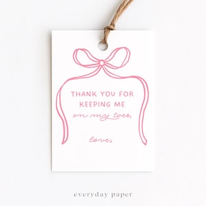 Könnte beinhalten: Ein weißes Geschenk-Etikett mit einem rosa Schleifen-Design und dem Text "THANK YOU FOR KEEPING ME on my toes, love,". Das Etikett ist mit Naturfaden versehen. Der Text "everyday paper" befindet sich unten.