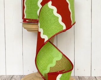 May include: Red and green ribbon with a white wavy design. The ribbon is on a wooden spool.