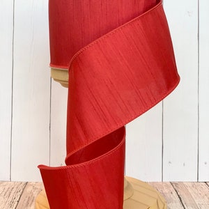 May include: A spool of red satin ribbon with a wired edge. The ribbon is 2.5 inches wide and has a subtle shimmer.