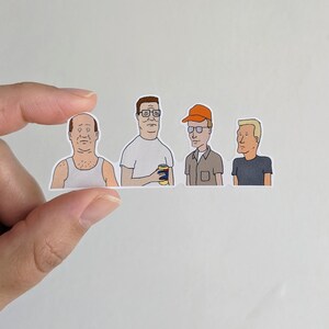 Op de afbeelding: Vier cartoonfiguren uit de animatieserie King of the Hill. De personages zijn Hank Hill, Dale Gribble, Boomhauer en Bill Dauterive. De personages zijn afgebeeld in hun kenmerkende stijlen, waarbij Hank een blauw shirt en een kaki broek draagt, Dale een groen shirt en een kaki broek draagt, Boomhauer een rood shirt en een blauwe spijkerbroek draagt en Bill een wit shirt en een blauwe spijkerbroek draagt.