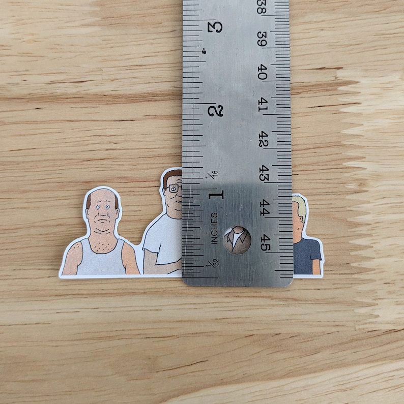 Op de afbeelding: Drie cartoon-personage stickers van mannen uit de animatieserie "King of the Hill". De stickers zijn ongeveer 2,5 cm hoog en zijn gedrukt op wit papier.