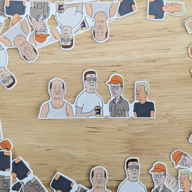 Op de afbeelding: Een set van negen cartoon stickers met personages uit de animatieserie King of the Hill. De stickers zijn gedrukt op wit papier en bevatten verschillende personages uit de show, waaronder Hank Hill, Peggy Hill, Bobby Hill en Dale Gribble.