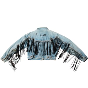 Könnte beinhalten: Eine hellblaue Jeansjacke mit schwarzen Fransen an den Rändern und dem Schriftzug "til death" auf der Rückseite.