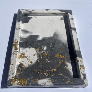 May include: A rectangular tray made of concrete with a white and gray marbled design and gold flecks.