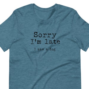 May include: A teal blue t-shirt with the text "Sorry I'm late I saw a dog" printed in black.
