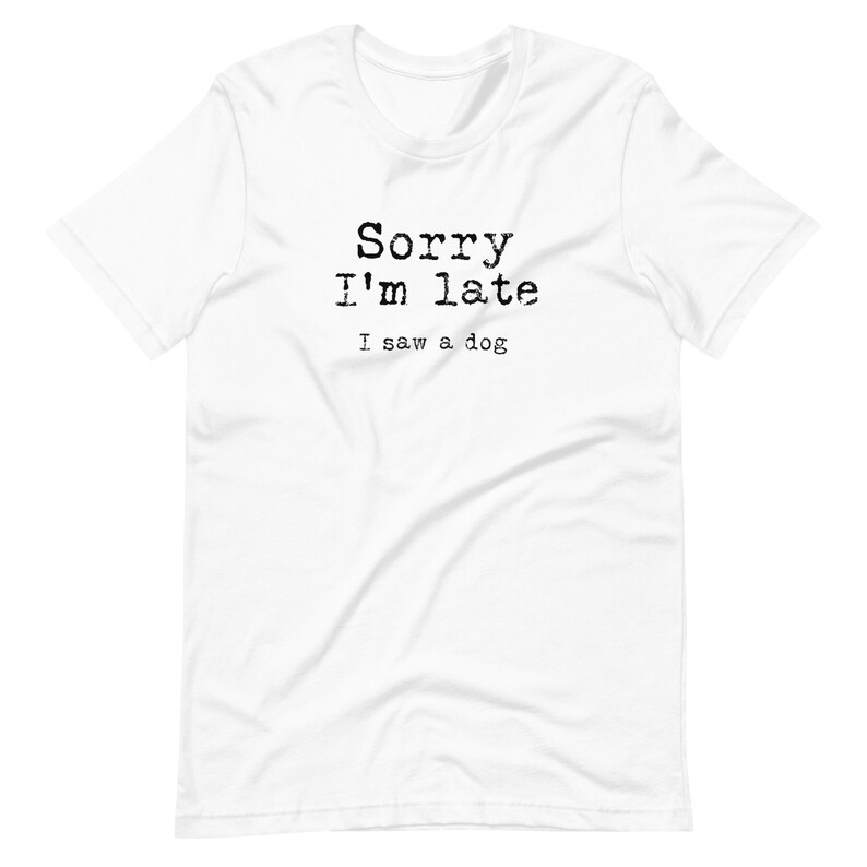 May include: White t-shirt with black text that reads "Sorry I'm late I saw a dog."