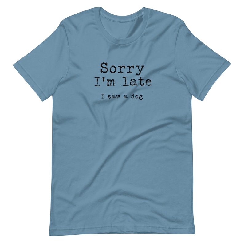 May include: A light blue t-shirt with the text "Sorry I'm late I saw a dog" printed in black.