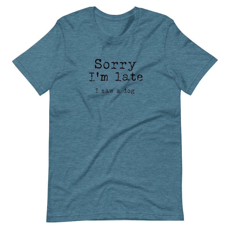 May include: A teal blue t-shirt with the text "Sorry I'm late I saw a dog" printed in black.