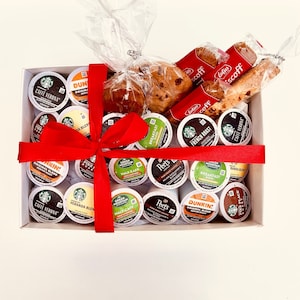 May include: A white gift box filled with a variety of coffee pods, including Green Mountain, Peet's, Dunkin', and Caffe Verona. The box is tied with a red ribbon and includes two pastries.